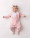 Pink and white baby sleepsuit with frilled bib and bows