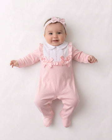 Pink and white baby sleepsuit with frilled bib and bows