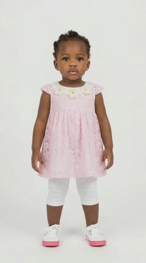 Black toddler girl in a pink lace swing dress with flower detail at the neck and white leggings on a light background.