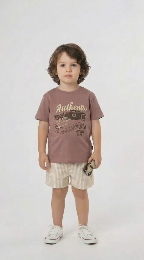 Young boy in a mocha authentic graphic t shirt and co ordinating shorts on a light background.
