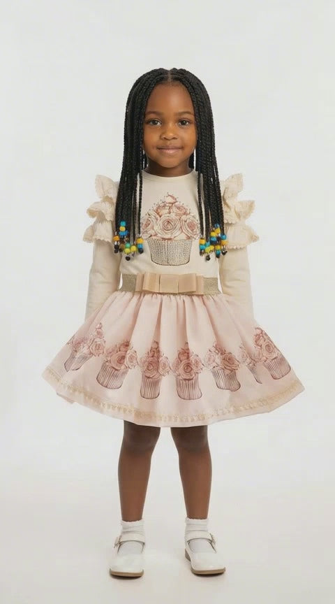 Young black girl with long braids in a cream sparkly cupcake top and matching skirt set.