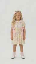 Pastel lemon floral dress with pink rabbit smocking and a white  Peter Pan collar on a blonde young girl.