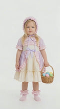 Child in a pastel bo peep style dress and matching bonnet holding a basket of pastel easter eggs