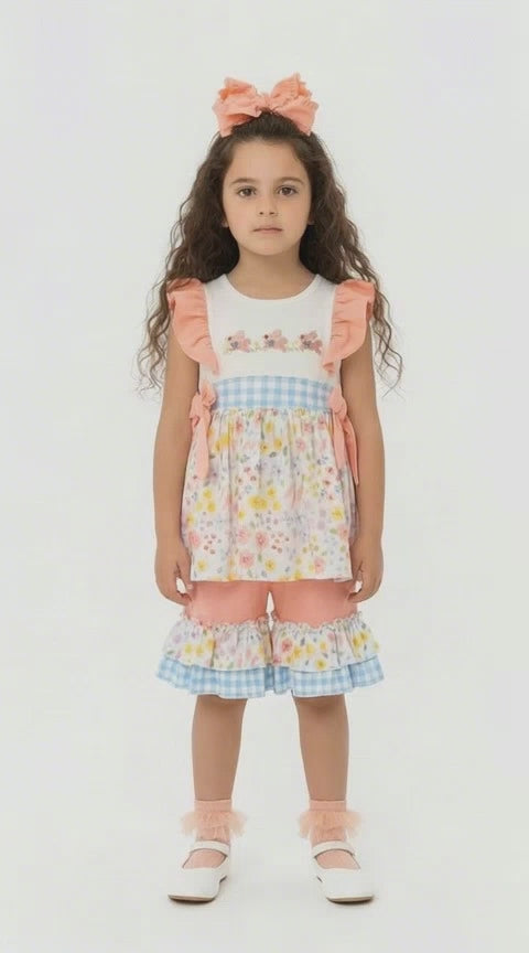Young girl in a 2 piece frill top and pedal pushers set in peach, pale florals and blue and white gingham 