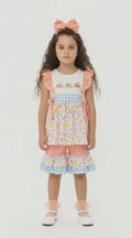 Young girl in a 2 piece frill top and pedal pushers set in peach, pale florals and blue and white gingham 
