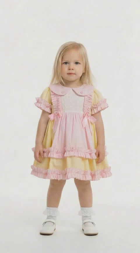 blonde hair toddler in a lemon and pink frilled dress on a white background