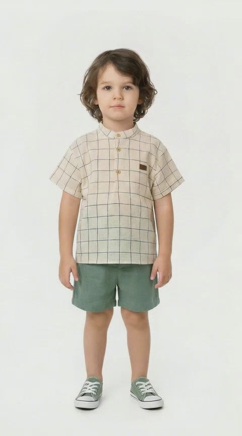 Young boy in a natural and green striped shirt with grandad collar and a co ordinating pair of green linen shorts