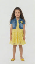 Girl with dark long hair in a lemon lace tiered dress with denim shrug on a light background.