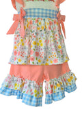 Children's outfit with floral topand ruffled shorts on a white background