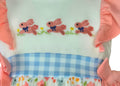 Children's top with embroidered bunnies and a checkered band on a white background