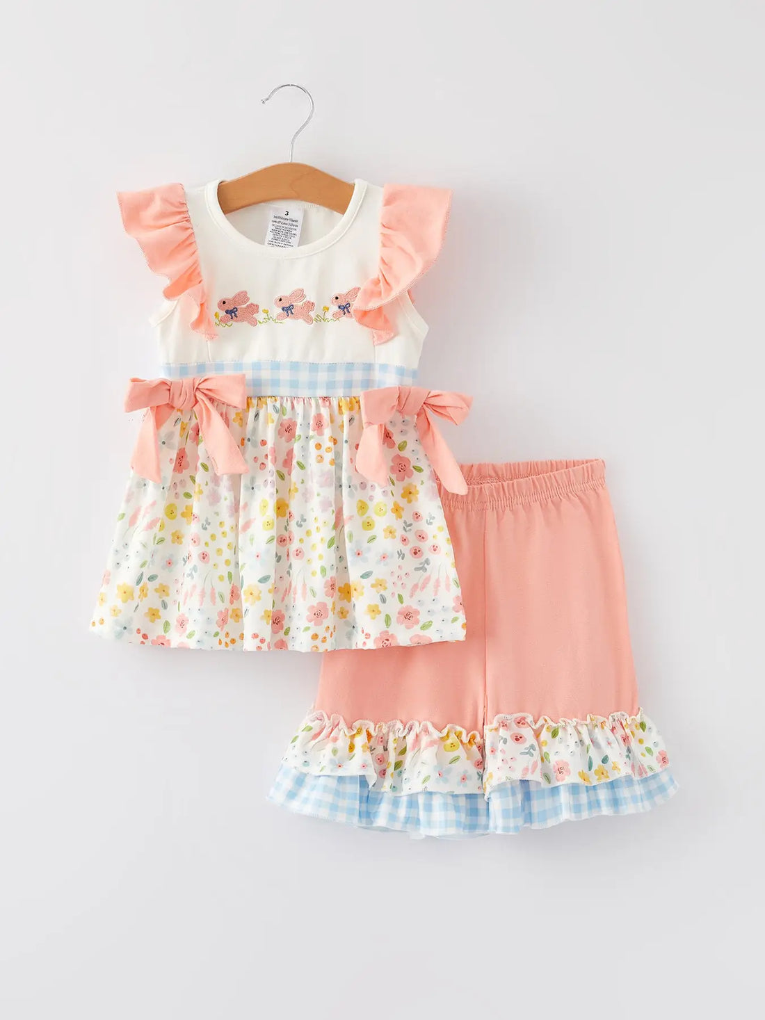 Young girl in a 2 piece frill top and pedal pushers set in peach, pale florals and blue and white gingham 