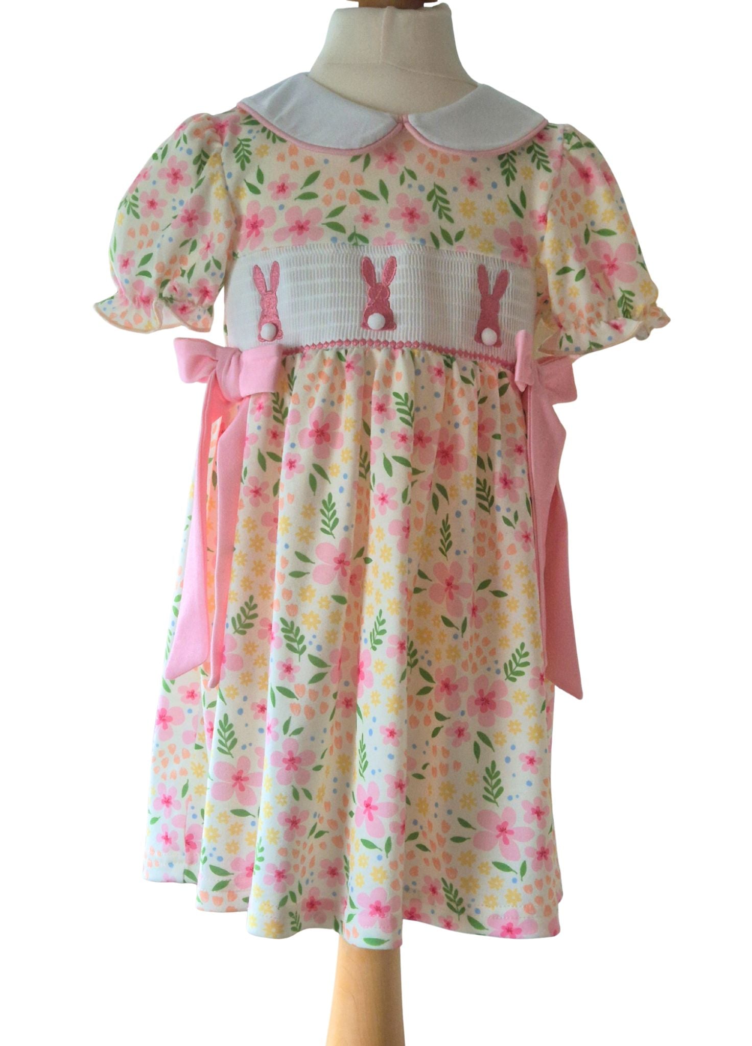 Children's dress with floral and bunny pattern on a mannequin against a white background