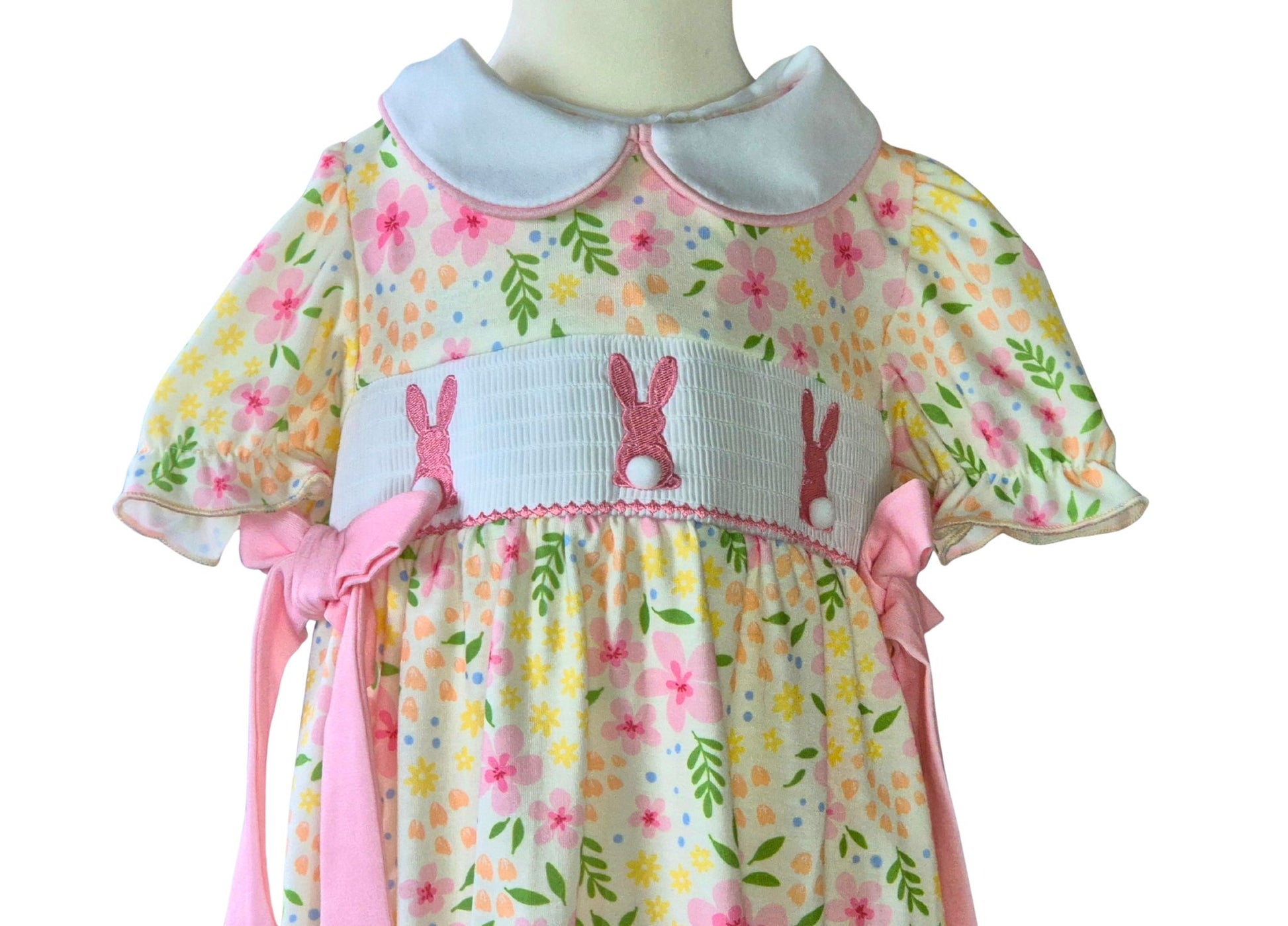 Babys romper with floral and bunny pattern on a mannequin against a white background