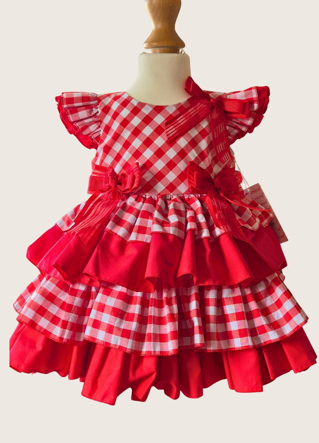 Video of a toddler with black curly hair in a red and white gingham check tiered dress.  Smiling and swaying her hips.
