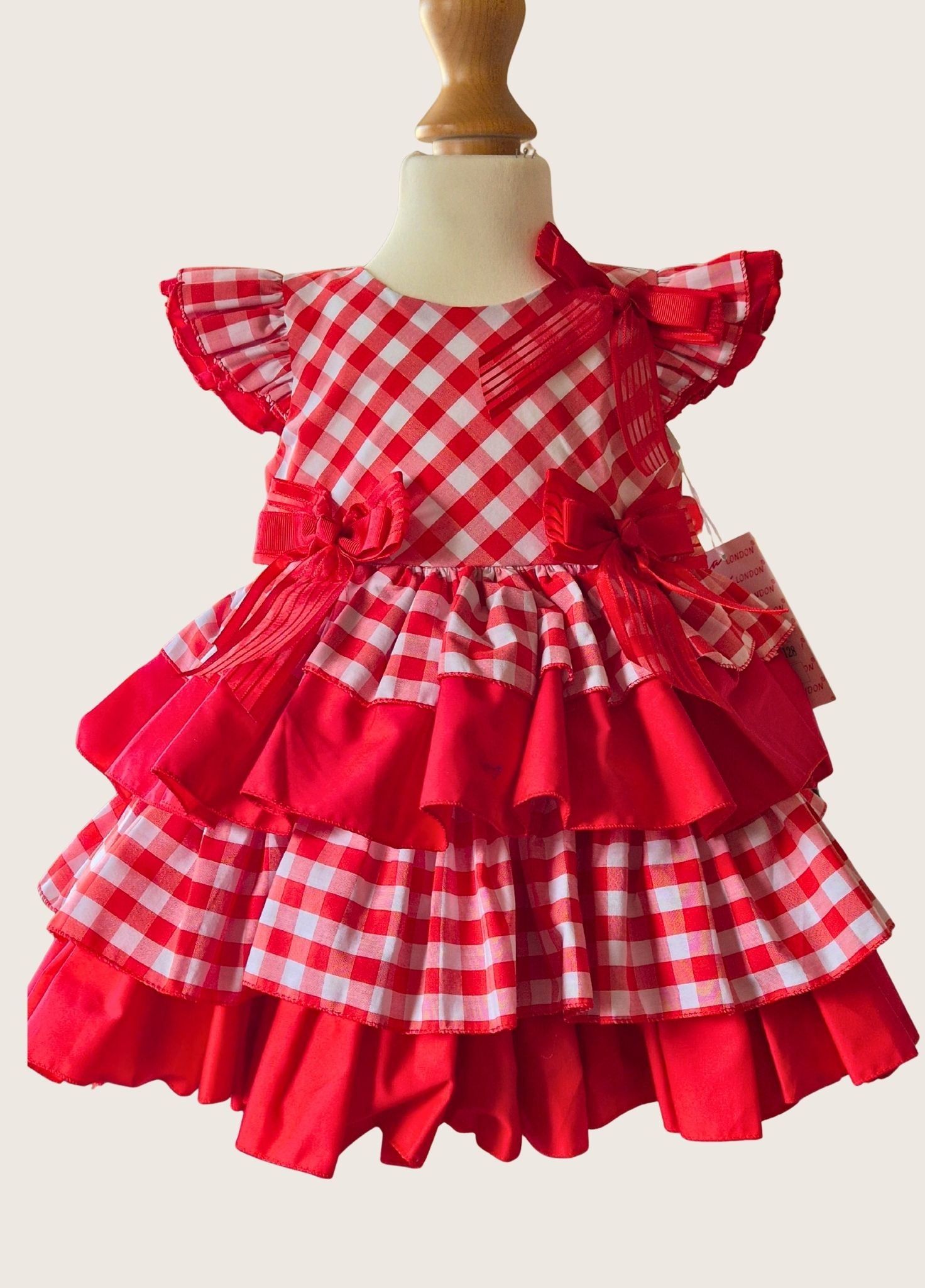 Red and white checkered dress with ruffles on a mannequin against a plain background