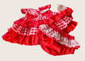 Red checkered baby dress with matching bloomers on a beige background