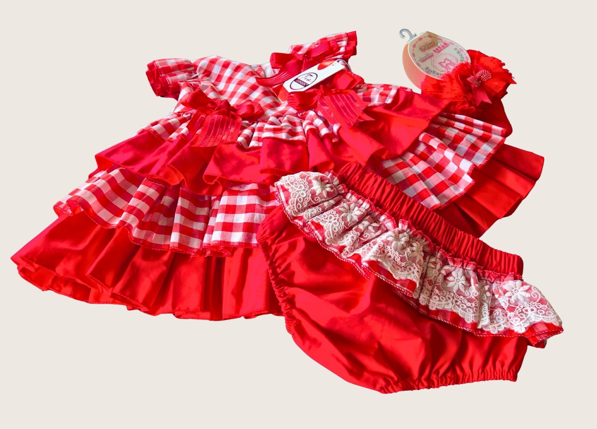 Red checkered baby dress with matching bloomers on a beige background