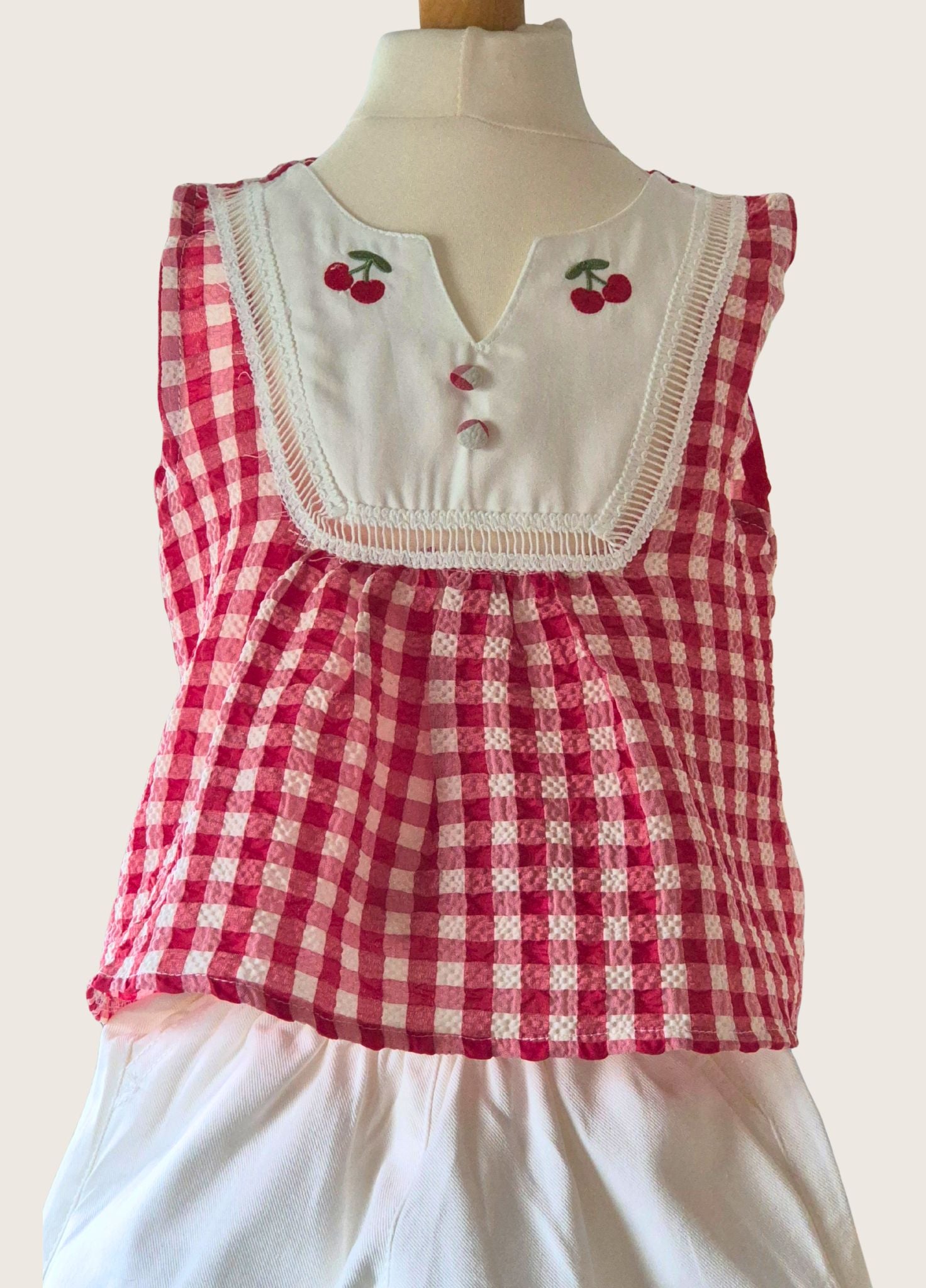Red and white checkered top with cherry details on a mannequin against a white background