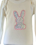 An off-white long-sleeve baby bodysuit featuring a sequined bunny applique on the chest with a pink border.