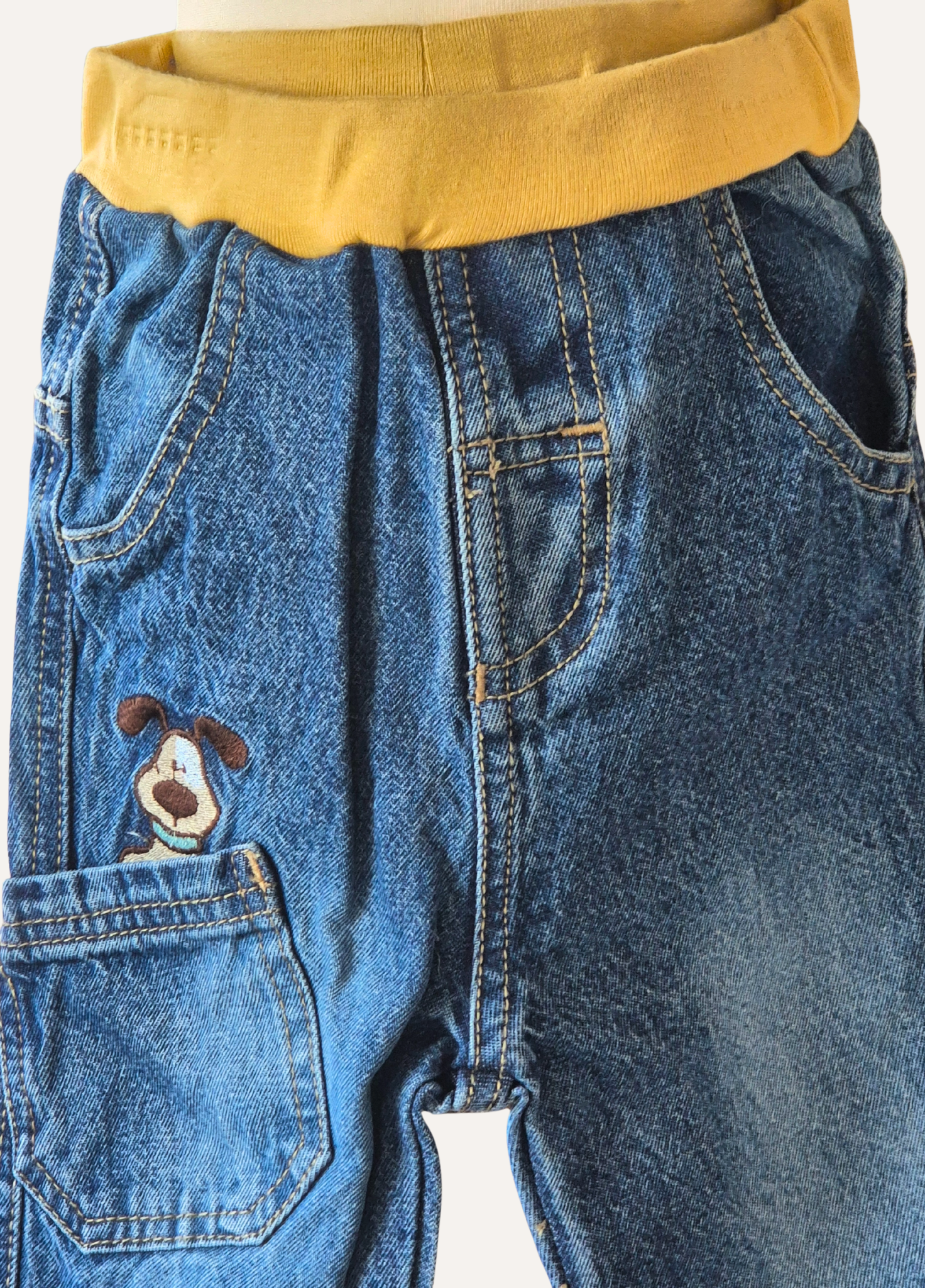 Close-up of boys blue jeans with the dog applique in the pocket 
