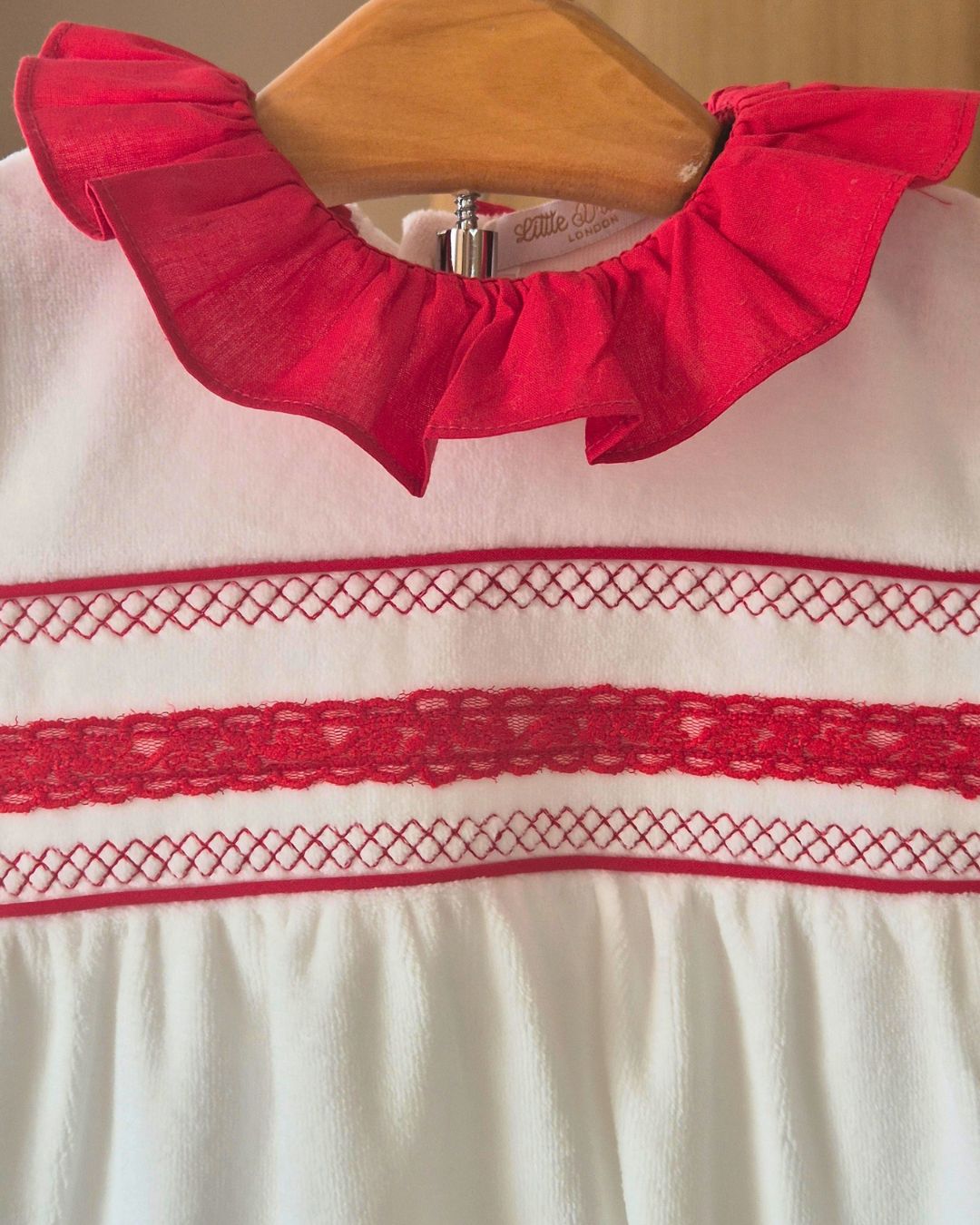 White baby sleepsuit with red cotton frill collar