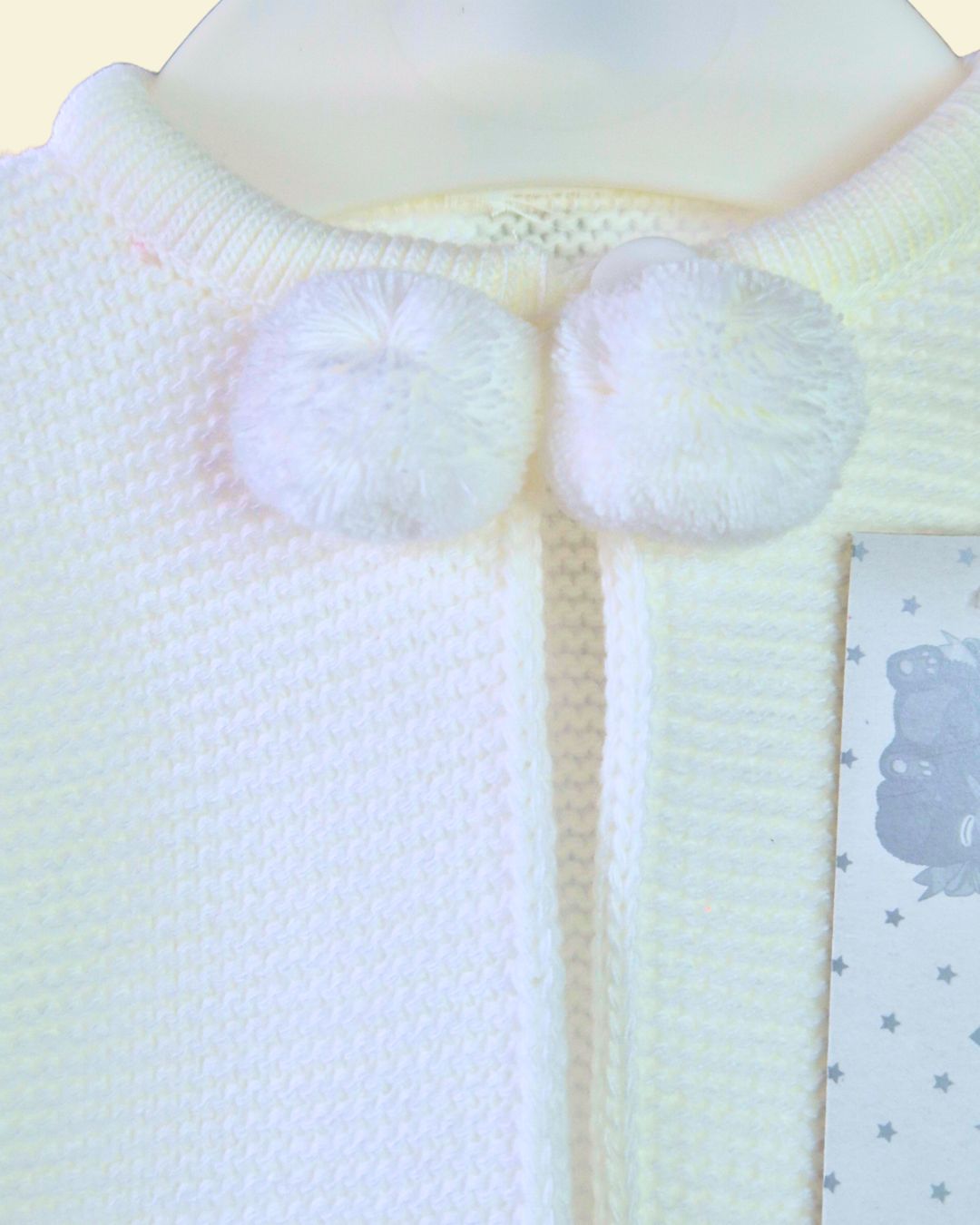White knitted baby cardigan with decorative pom poms